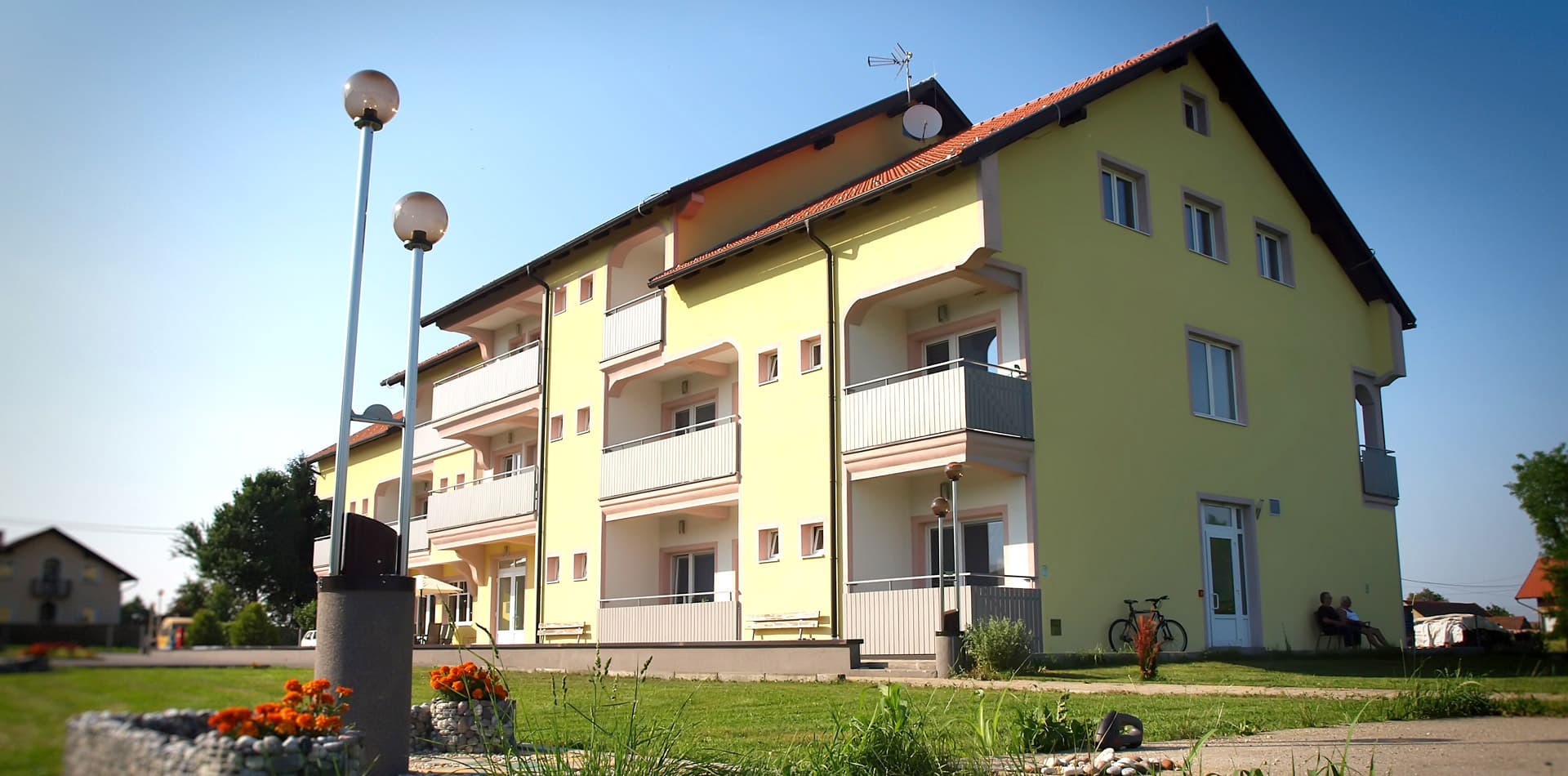 Pročelje Doma Petrović s balkonima, uličnim svjetiljkama i cvjetnim gredicama